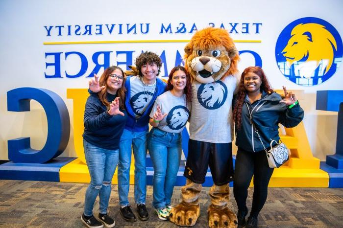 Four students pose with Lucky the 狮子 mascot.
